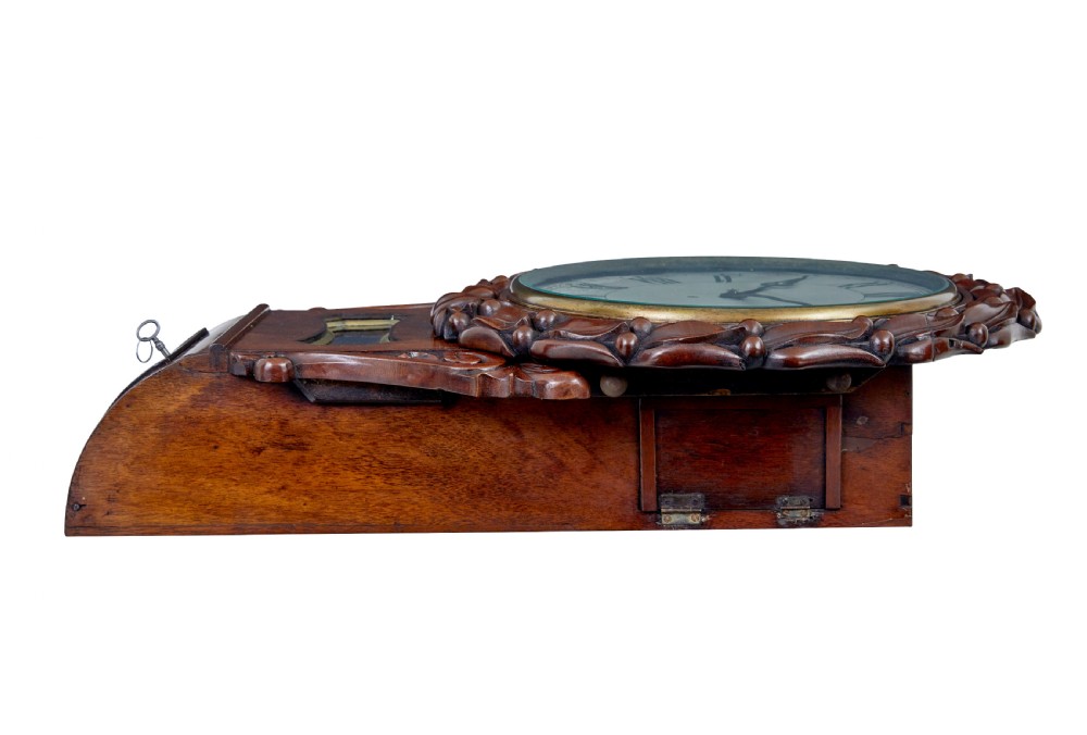 A mid-19th century Victorian mahogany fusee wall clock featuring a hand-carved foliate surround, white dial with Roman numerals, and a lower pendulum window. View IV