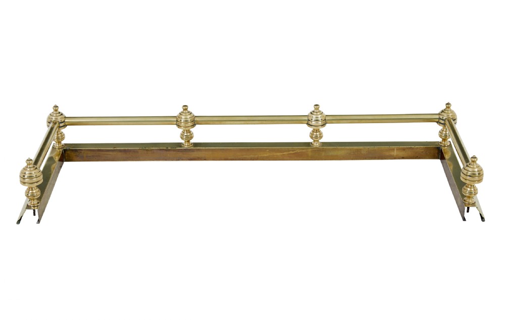An early 20th-century polished brass fireside fender featuring a stepped base and a raised top rail supported by turned spherical finials. View IV