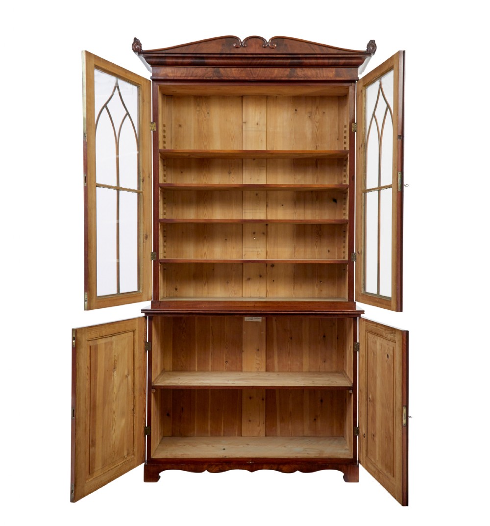 An early 19th-century flame mahogany bookcase featuring a pediment top, two upper glazed doors with arched astragal glazing, and a double-door cupboard base. View II
