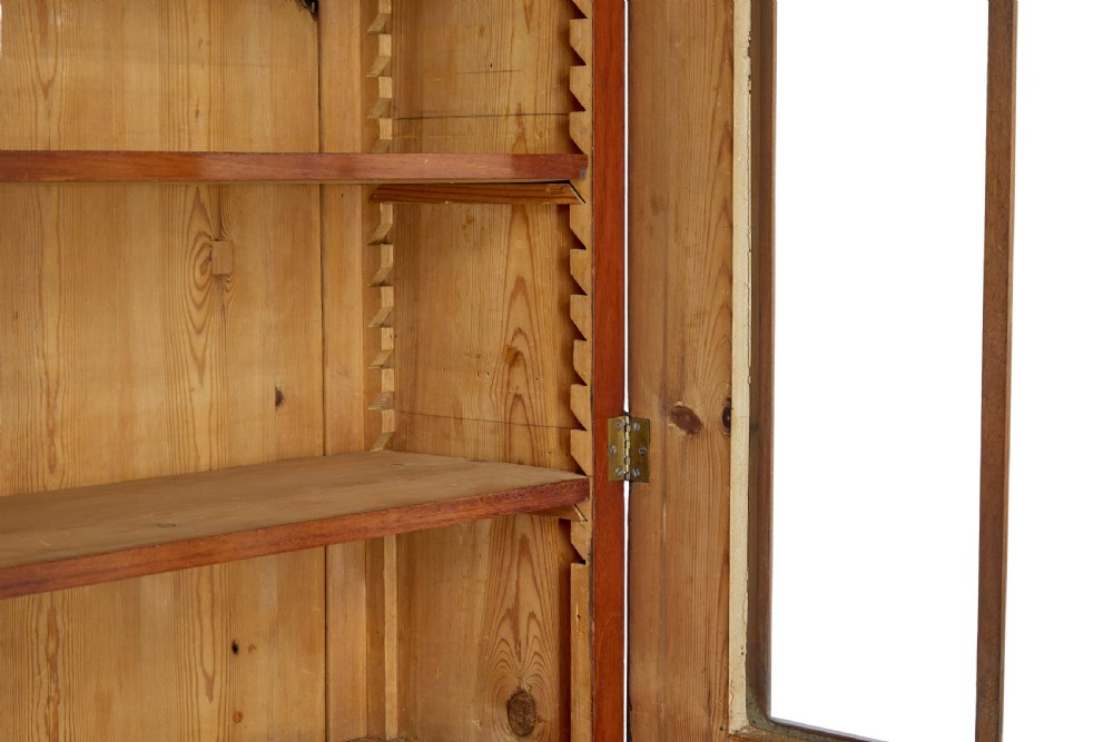 An early 19th-century flame mahogany bookcase featuring a pediment top, two upper glazed doors with arched astragal glazing, and a double-door cupboard base. View VII