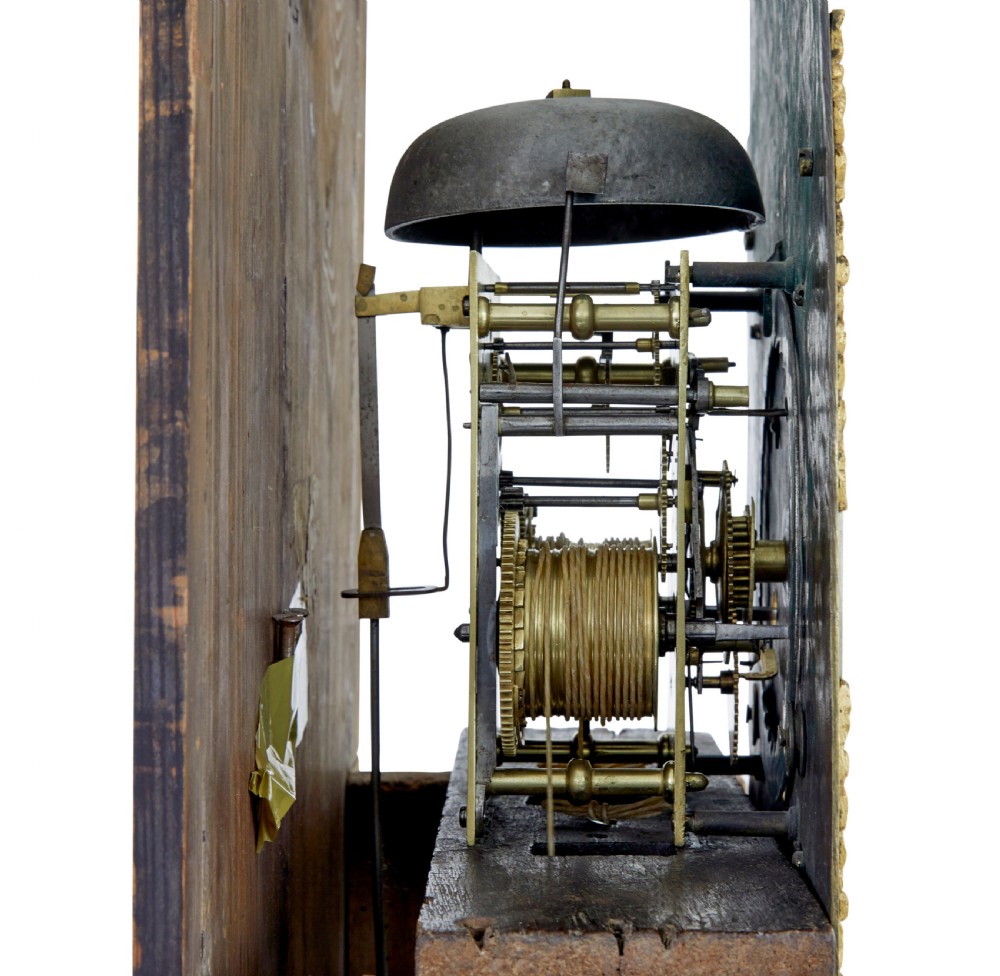 An 18th-century oak longcase clock featuring a brass dial, pediment hood with brass finials, rectangular trunk door, and plinth base. View X