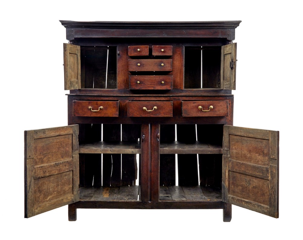 A seventeenth-century dark oak Welsh court cupboard featuring raised geometric panels, turned pendant drops, small central drawers, and double lower doors. View III