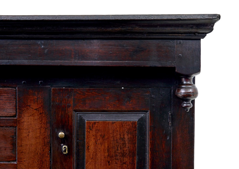A seventeenth-century dark oak Welsh court cupboard featuring raised geometric panels, turned pendant drops, small central drawers, and double lower doors. View IV