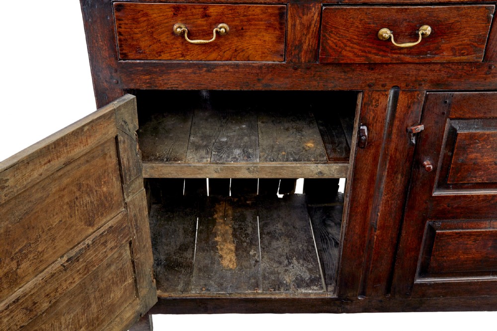A seventeenth-century dark oak Welsh court cupboard featuring raised geometric panels, turned pendant drops, small central drawers, and double lower doors. View IX