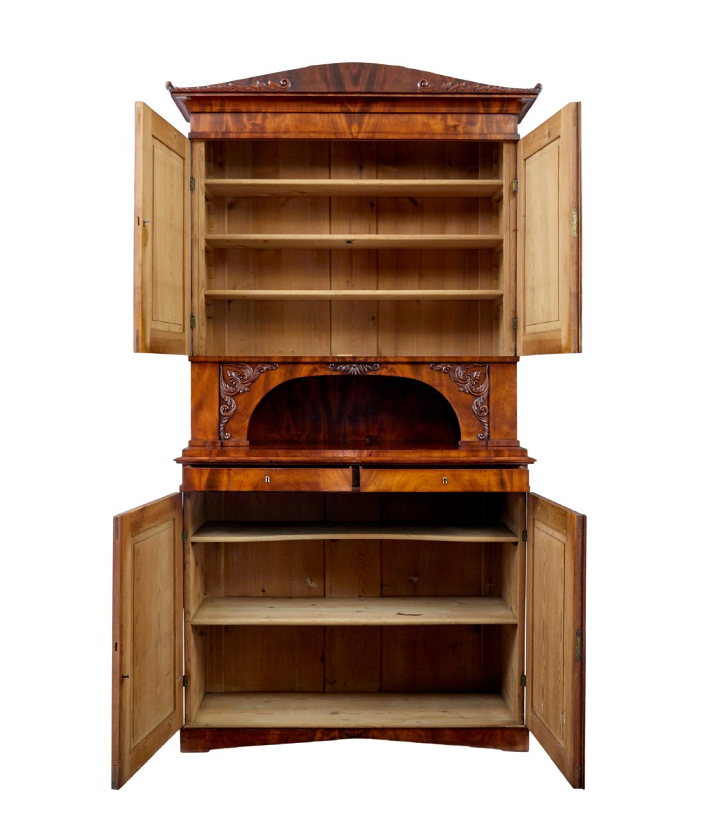 A mid-19th-century Danish flame mahogany tall cabinet featuring a carved cresting pediment, open central niche, and double cupboard doors with moulded panels. View II