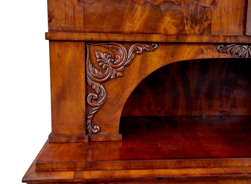 A mid-19th-century Danish flame mahogany tall cabinet featuring a carved cresting pediment, open central niche, and double cupboard doors with moulded panels. View VI