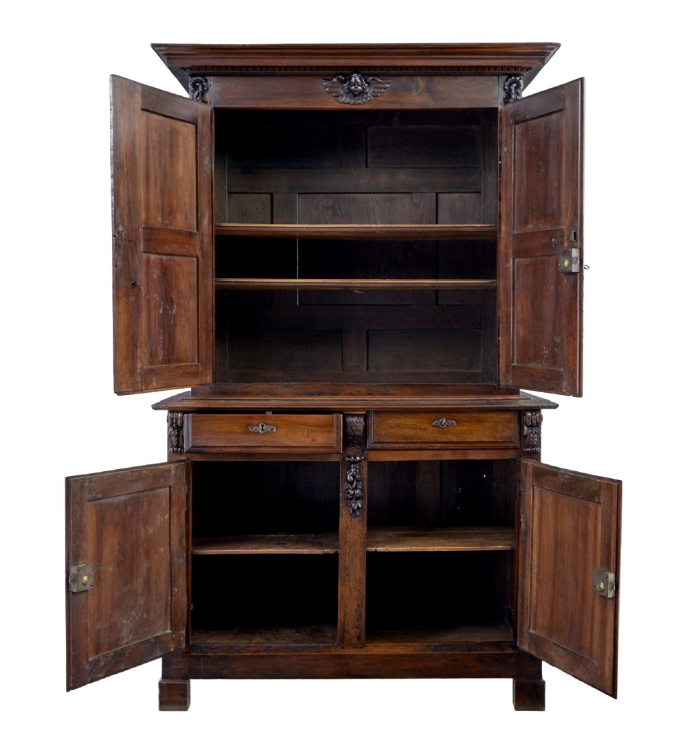 An eighteenth-century French carved walnut cupboard in two tiers featuring geometric relief panels, floral motifs, cherub carvings, and decorative steel hinges. View II