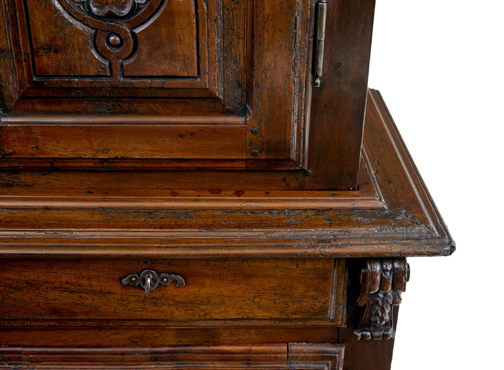 An eighteenth-century French carved walnut cupboard in two tiers featuring geometric relief panels, floral motifs, cherub carvings, and decorative steel hinges. View IX