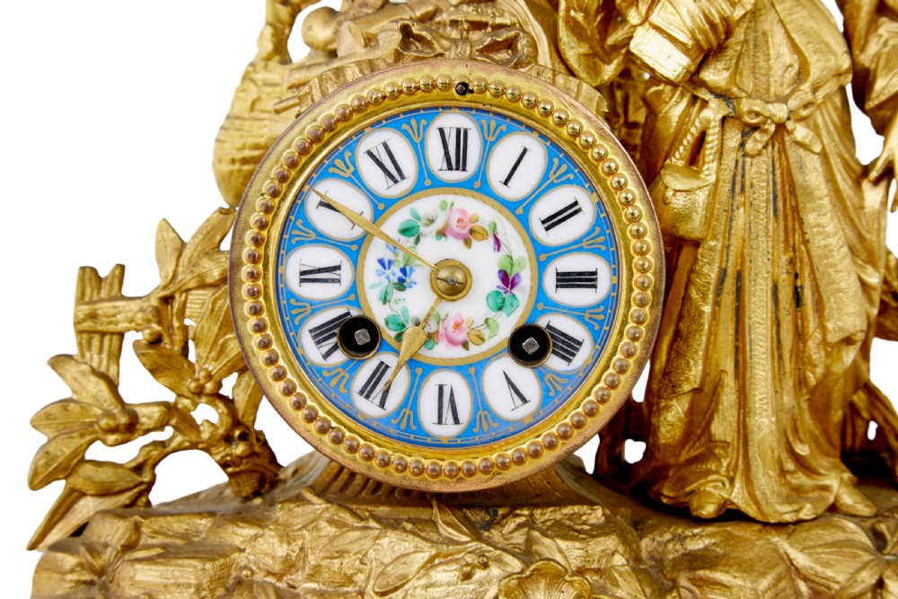 An ornate 19th-century French gilt metal mantel clock featuring a sculpted female figure, Rococo scrollwork, and hand-painted turquoise blue porcelain plaques. View VII