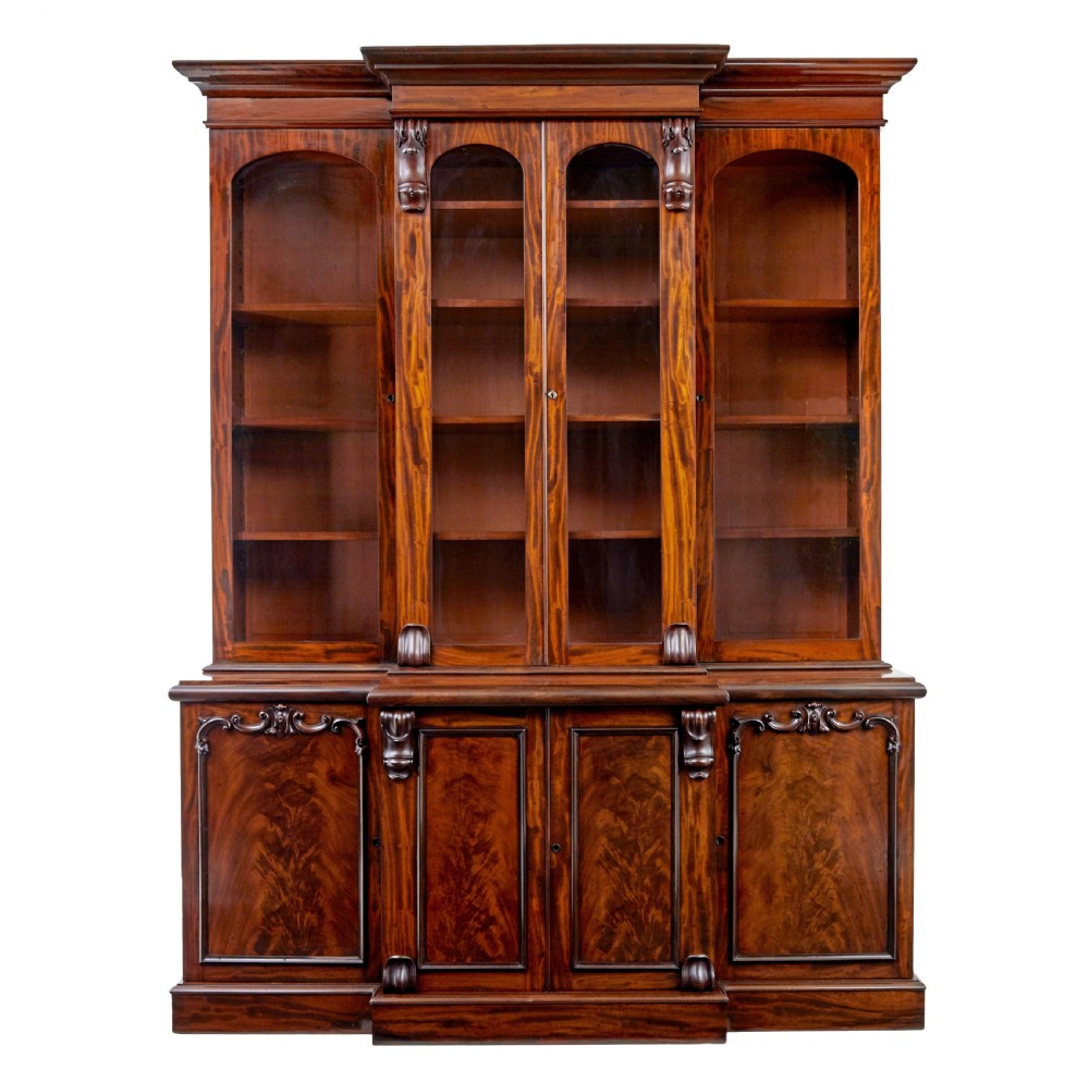 A large early Victorian flame mahogany breakfront bookcase featuring glazed upper doors and panelled lower cupboard doors.