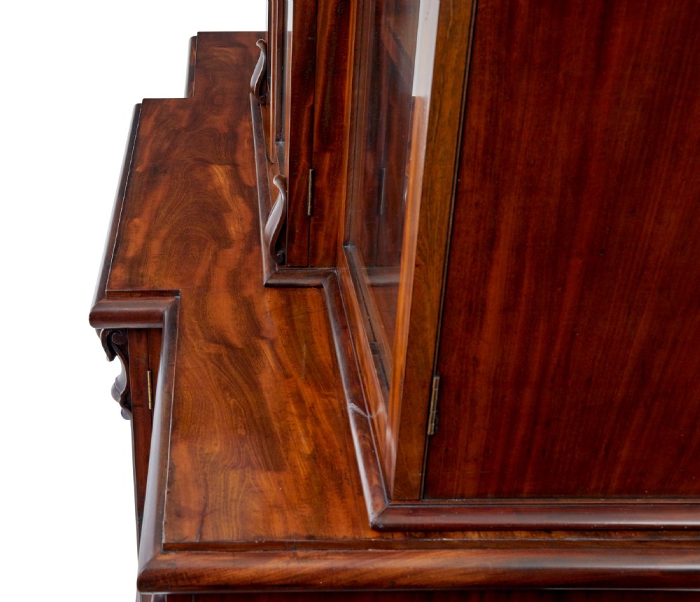 A large early Victorian flame mahogany breakfront bookcase featuring glazed upper doors and panelled lower cupboard doors. View IX