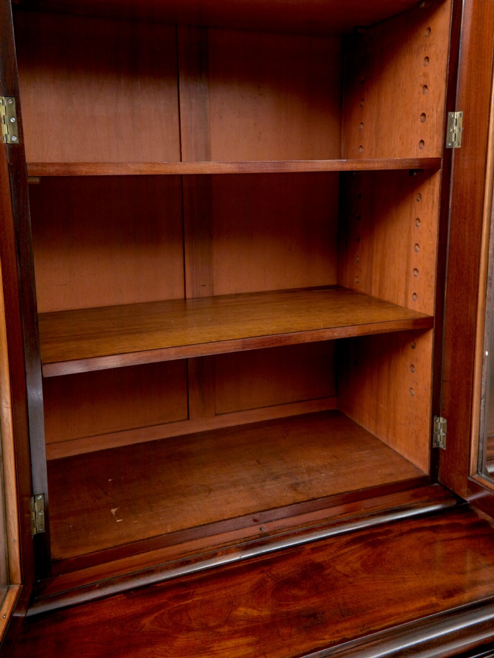 A large early Victorian flame mahogany breakfront bookcase featuring glazed upper doors and panelled lower cupboard doors. View X