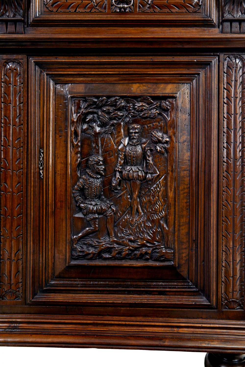 Mid 19th century dark walnut two-tiered Italian cabinet featuring intricately carved relief panels of figures, decorative drawers, and bun feet. View X