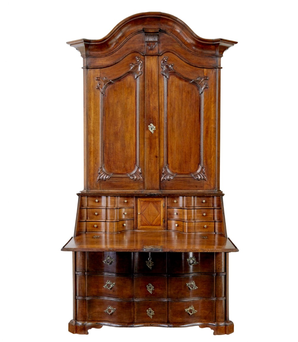 An 18th-century Norwegian carved oak bureau bookcase featuring an arched pediment, panelled upper doors, a slant-front writing slant, serpentine lower drawers, and brass escutcheons. View II