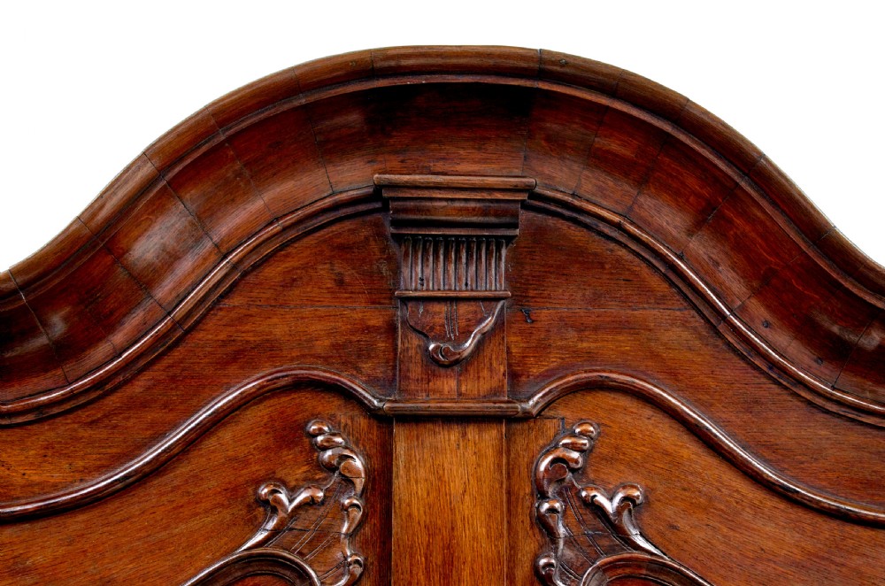 An 18th-century Norwegian carved oak bureau bookcase featuring an arched pediment, panelled upper doors, a slant-front writing slant, serpentine lower drawers, and brass escutcheons. View XI
