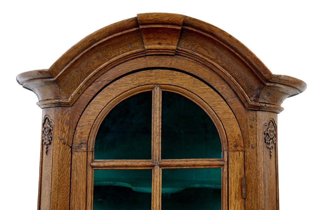 A mid-19th-century carved oak display cabinet featuring glazed doors, arched pediment, and green fabric interior lining. View IX