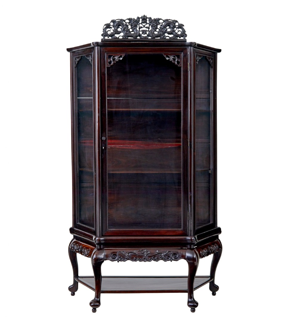 A 19th-century Chinese carved dark hardwood display cabinet featuring glazed doors, an intricate dragon cresting rail, and cabriole legs with a lower undertier.