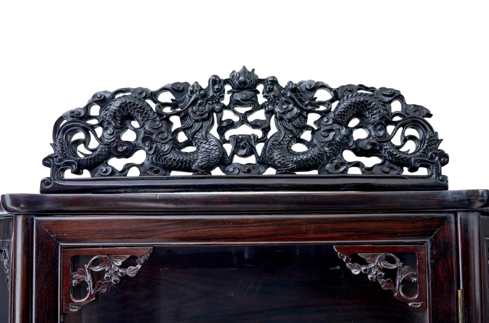A 19th-century Chinese carved dark hardwood display cabinet featuring glazed doors, an intricate dragon cresting rail, and cabriole legs with a lower undertier. View VII