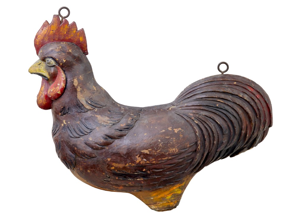 A 19th-century French carved solid wood rooster shop display with distressed painted surface layers and top iron hanging loops.