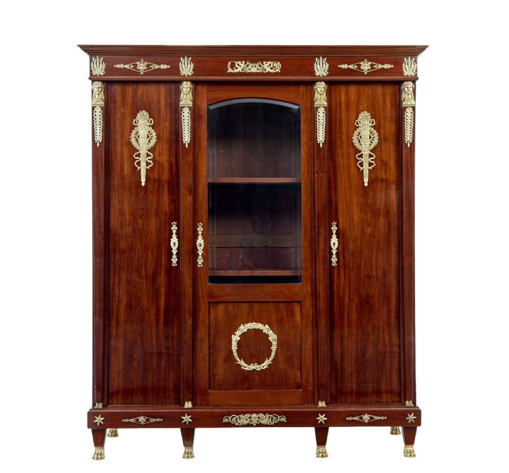 A late nineteenth-century French Empire style mahogany cabinet featuring three doors, central glass panelling, and ornate gold-coloured ormolu mounts. View II