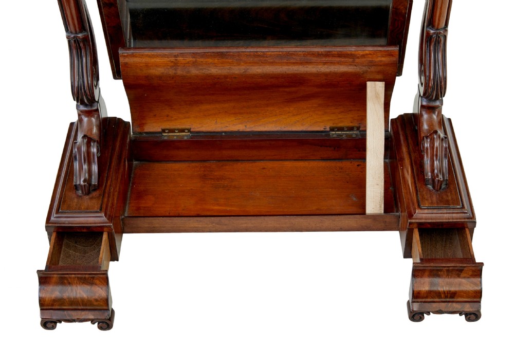 An Early Victorian mahogany toilet mirror featuring a rectangular frame set between carved scroll supports on a plinth base with scroll feet. View VI