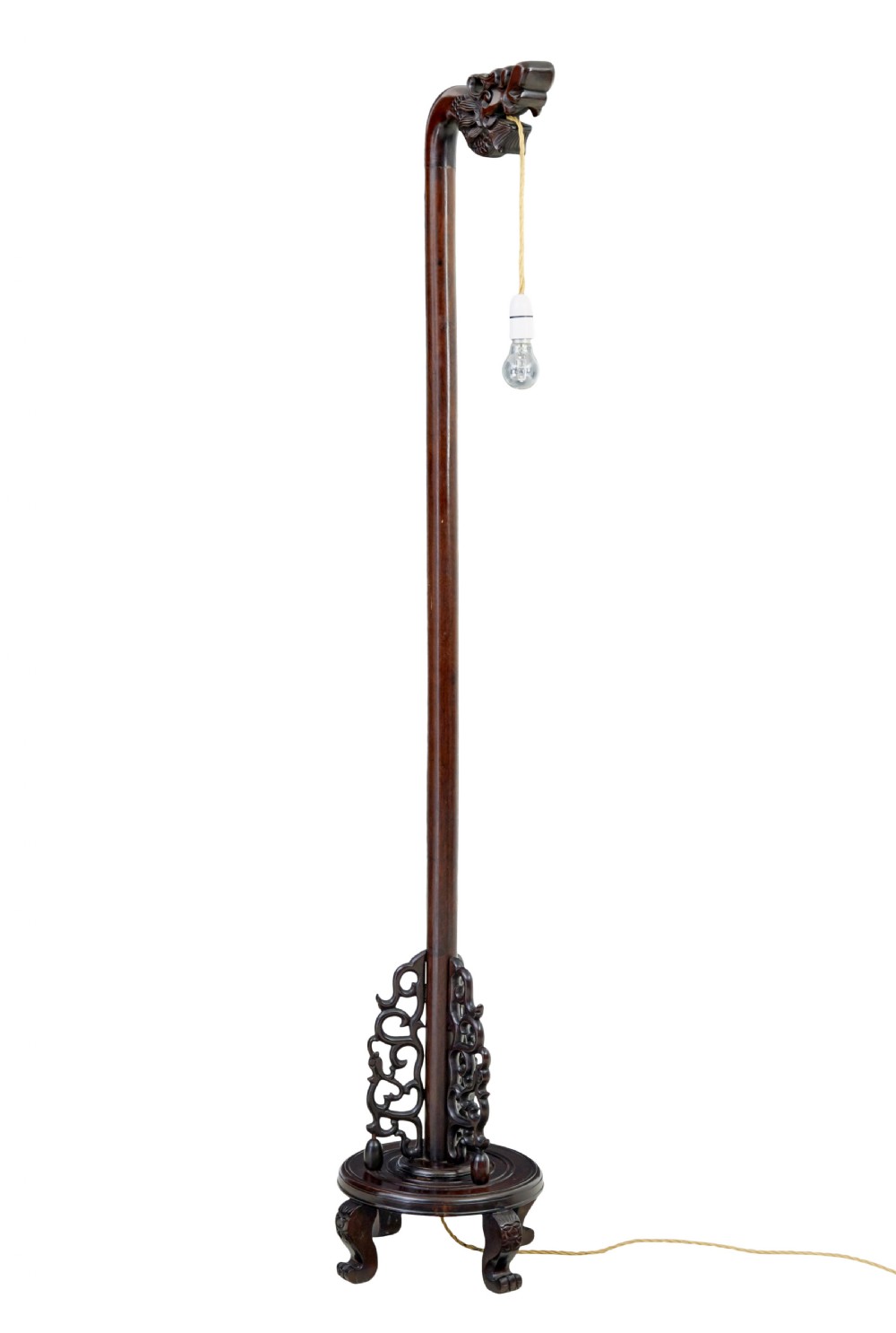A tall dark hardwood floor lamp featuring a carved dragon head top motif and an openwork carved base with cabriole feet.