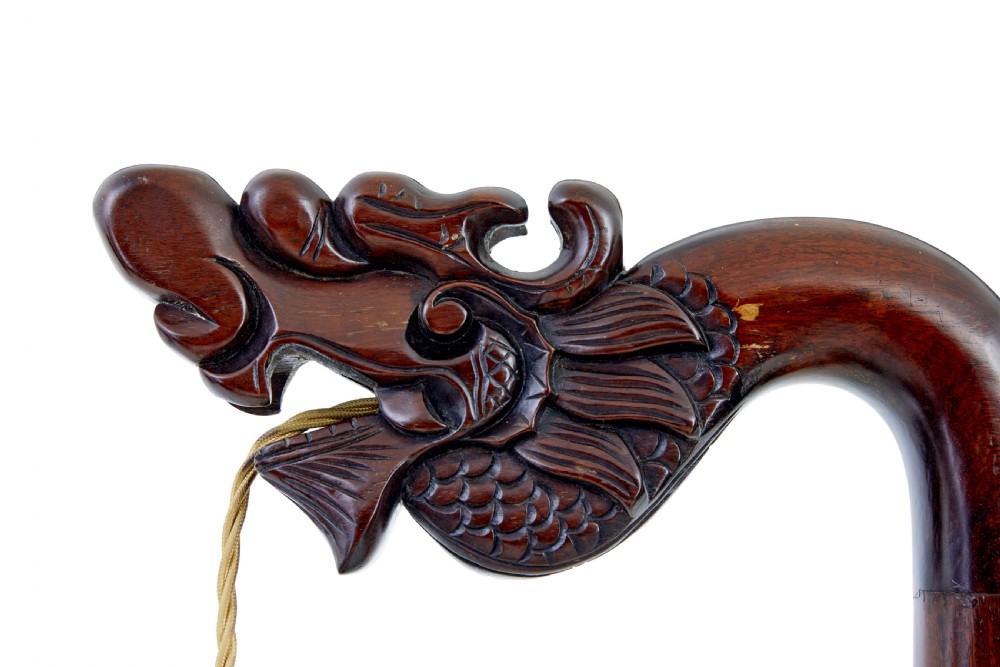 A tall dark hardwood floor lamp featuring a carved dragon head top motif and an openwork carved base with cabriole feet. View II