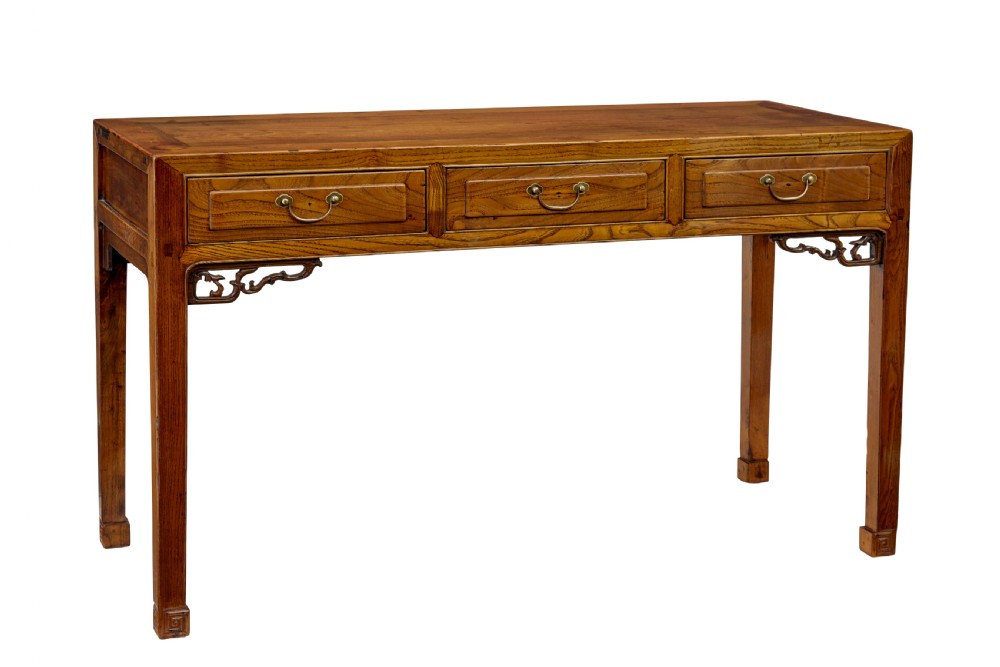 A 19th-century Chinese carved elm console table featuring three drawers with brass handles, carved corner spandrels, and square legs.