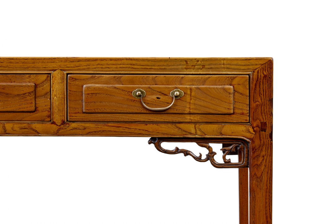 A 19th-century Chinese carved elm console table featuring three drawers with brass handles, carved corner spandrels, and square legs. View VII