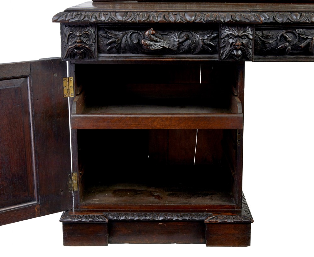 A 19th-century dark oak sideboard featuring twin carved pedestal cupboards, relief fruit swags, and an upper mirrored frame superstructure. View II