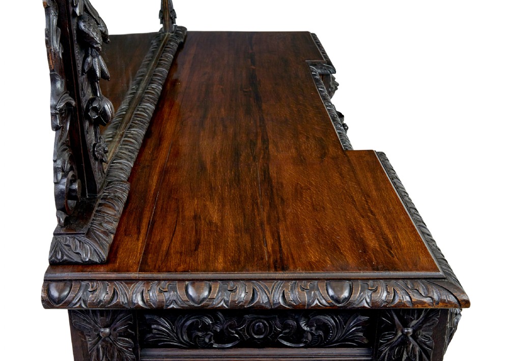 A 19th-century dark oak sideboard featuring twin carved pedestal cupboards, relief fruit swags, and an upper mirrored frame superstructure. View IX