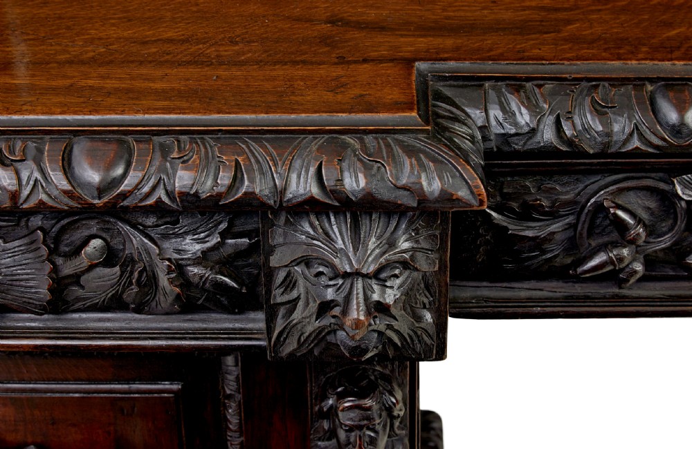 A 19th-century dark oak sideboard featuring twin carved pedestal cupboards, relief fruit swags, and an upper mirrored frame superstructure. View XI