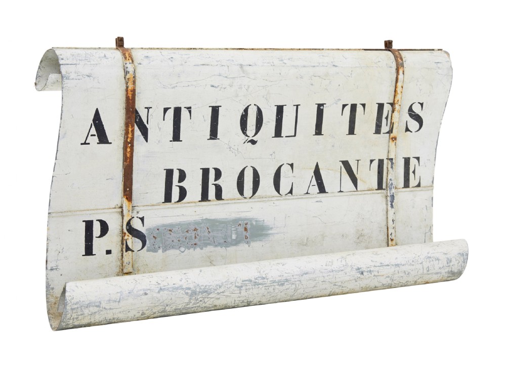 An early twentieth-century French sheet metal shop sign painted off-white with black stencilled lettering reading Antiquites Brocante and iron mounting straps.