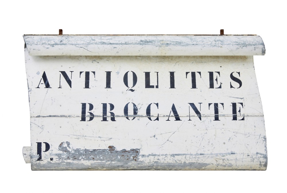 An early twentieth-century French sheet metal shop sign painted off-white with black stencilled lettering reading Antiquites Brocante and iron mounting straps. View II