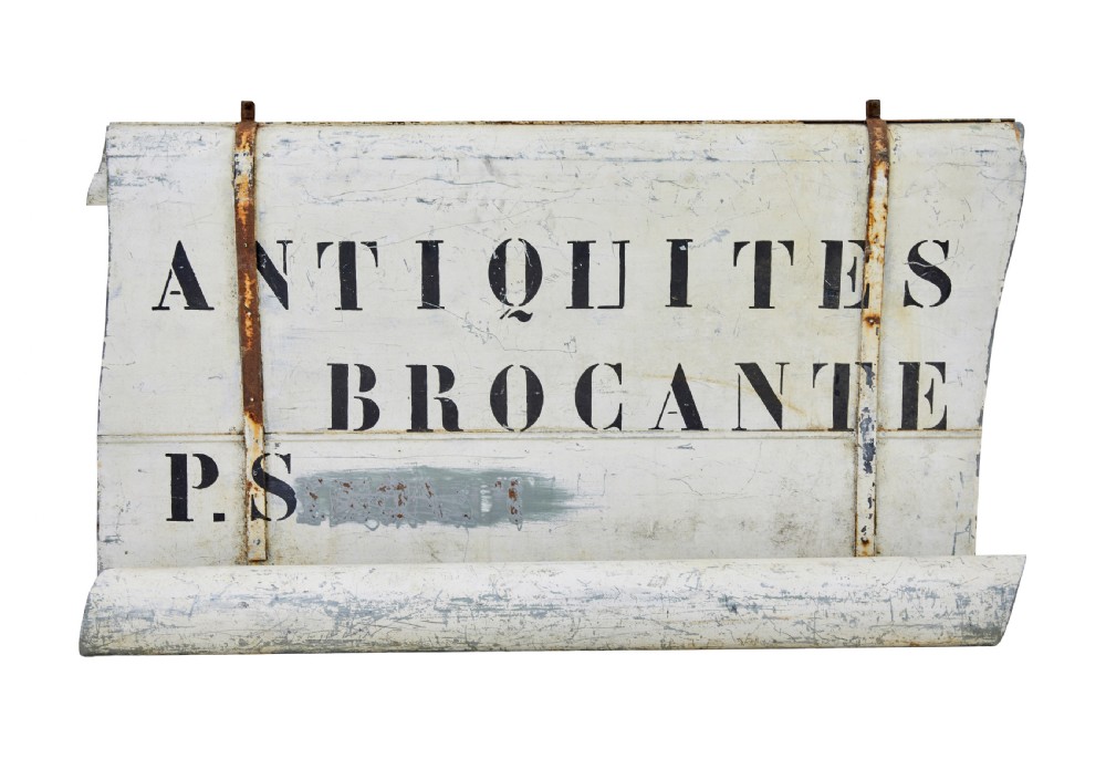 An early twentieth-century French sheet metal shop sign painted off-white with black stencilled lettering reading Antiquites Brocante and iron mounting straps. View III