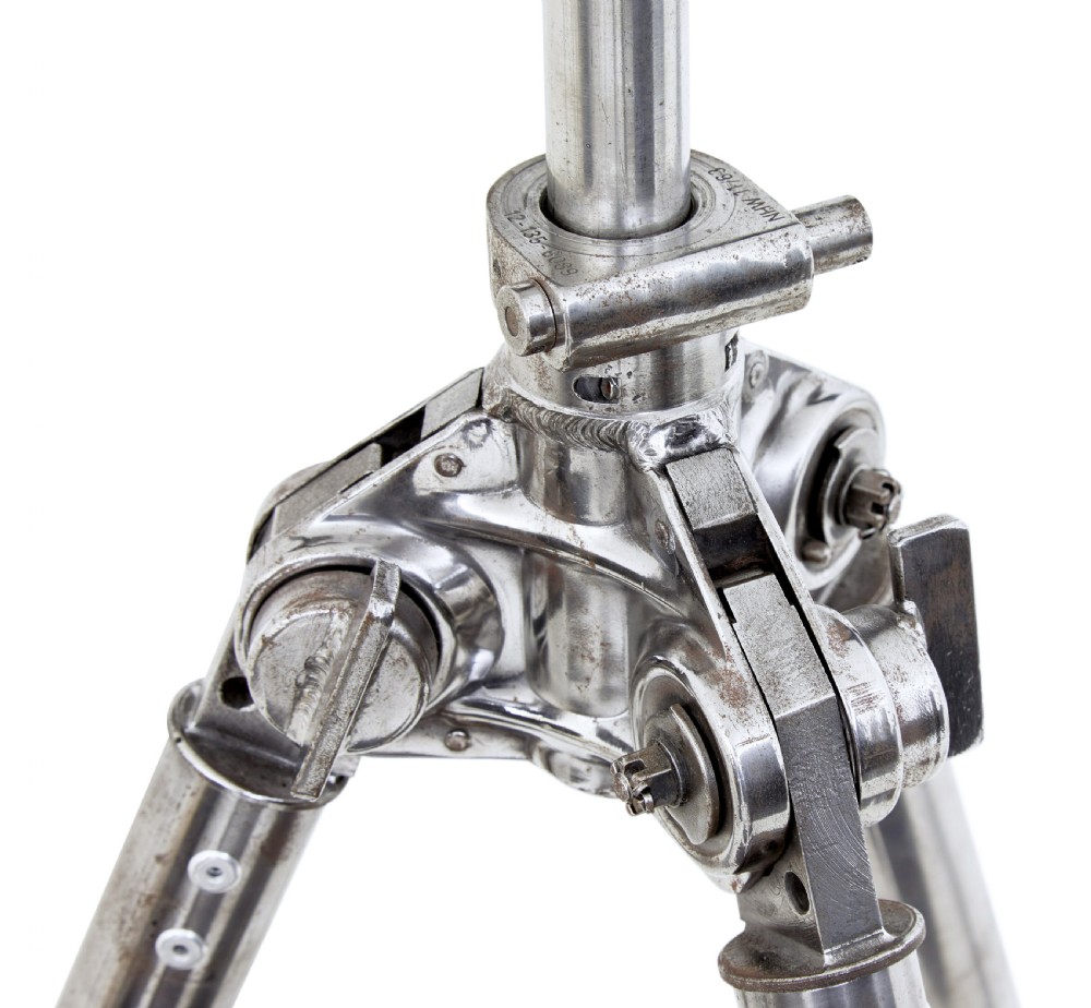 A pair of polished steel military binoculars mounted on a tall three-legged metal tripod stand against a plain background. View XVIII
