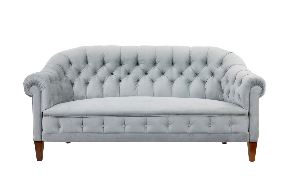 An early 20th-century three-piece suite comprising a two-seater sofa and two matching armchairs upholstered in light grey deep-buttoned velvet with tapered wooden legs. View II