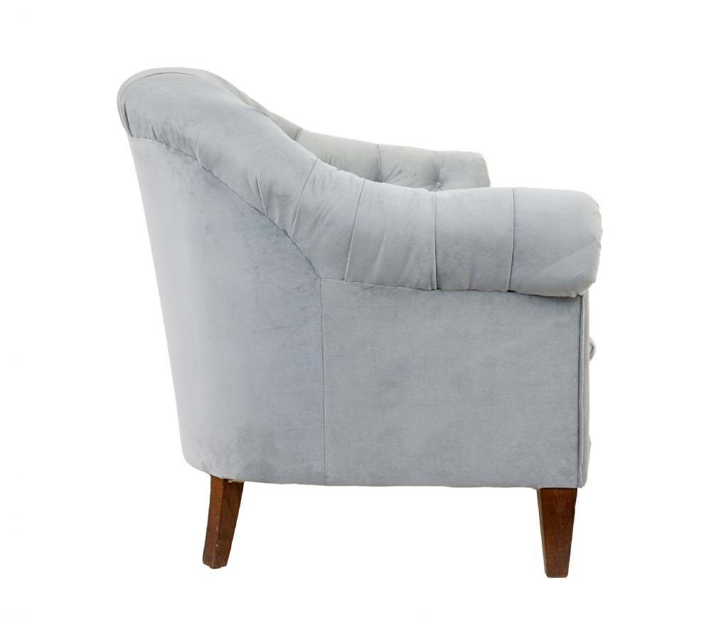An early 20th-century three-piece suite comprising a two-seater sofa and two matching armchairs upholstered in light grey deep-buttoned velvet with tapered wooden legs. View IV
