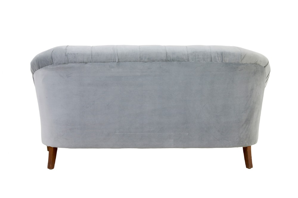 An early 20th-century three-piece suite comprising a two-seater sofa and two matching armchairs upholstered in light grey deep-buttoned velvet with tapered wooden legs. View V