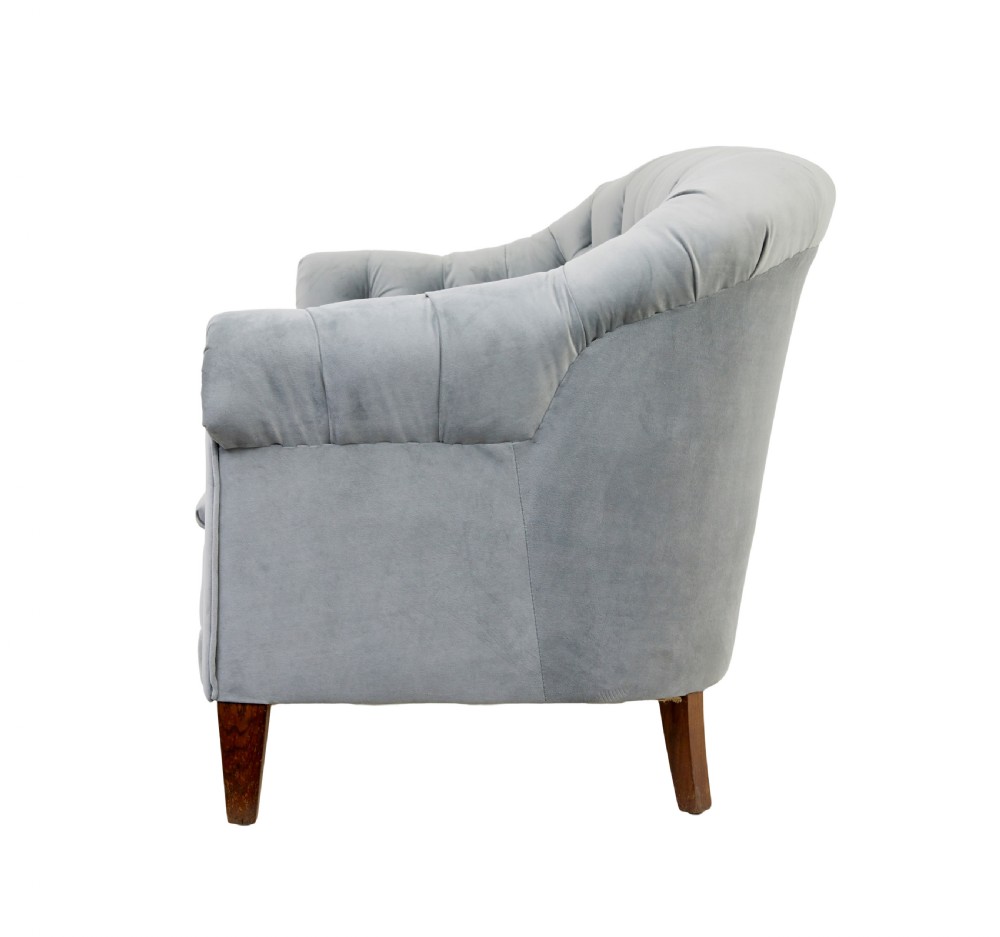 An early 20th-century three-piece suite comprising a two-seater sofa and two matching armchairs upholstered in light grey deep-buttoned velvet with tapered wooden legs. View VI