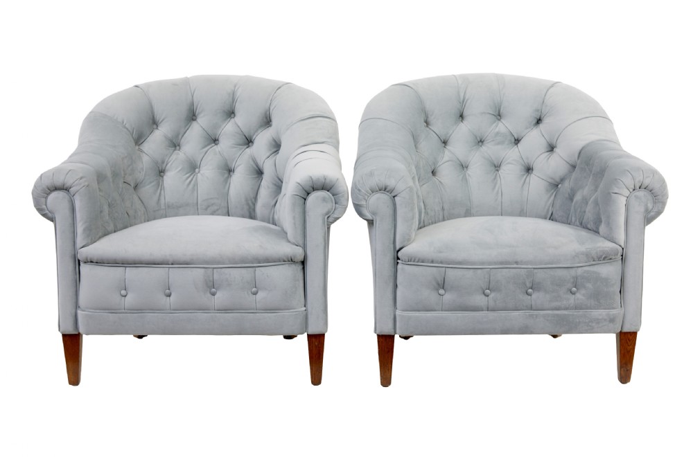 An early 20th-century three-piece suite comprising a two-seater sofa and two matching armchairs upholstered in light grey deep-buttoned velvet with tapered wooden legs. View X