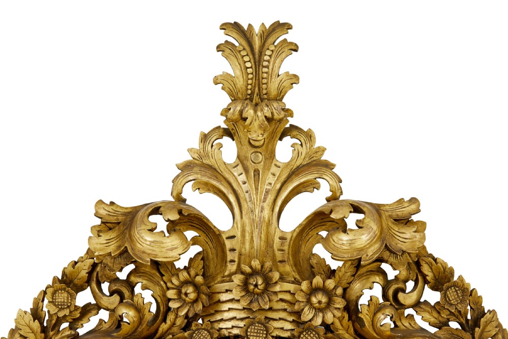 An ornate gold gilt wall mirror featuring a carved cushion frame decorated with floral motifs, scrollwork, and an etched oval glass crest. View III