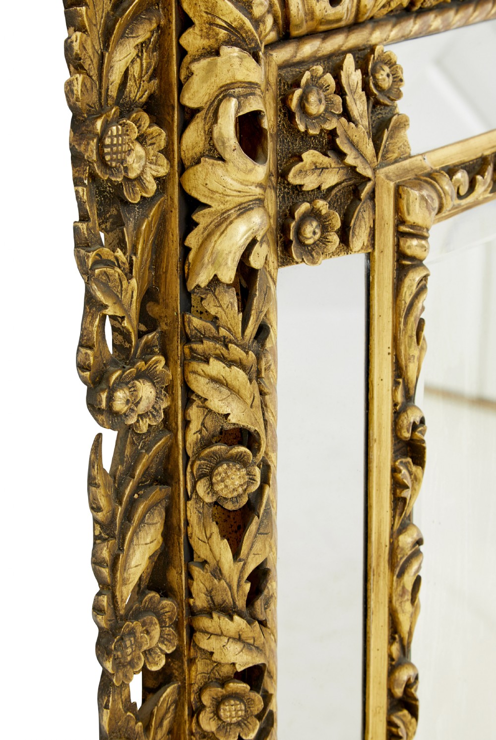 An ornate gold gilt wall mirror featuring a carved cushion frame decorated with floral motifs, scrollwork, and an etched oval glass crest. View VI