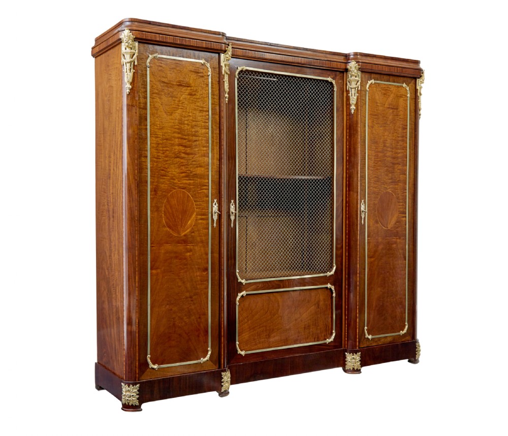 A nineteenth-century French Empire style mahogany cabinet featuring decorative ormolu mounts, a central brass wire mesh door, and outer panelled doors with shell inlays.