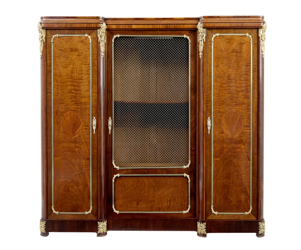 A nineteenth-century French Empire style mahogany cabinet featuring decorative ormolu mounts, a central brass wire mesh door, and outer panelled doors with shell inlays. View II