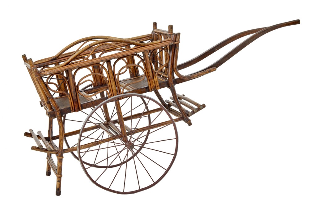 An early 20th-century oriental child carriage constructed from bent warm brown bamboo with two seats and large metal spoked wheels. View II