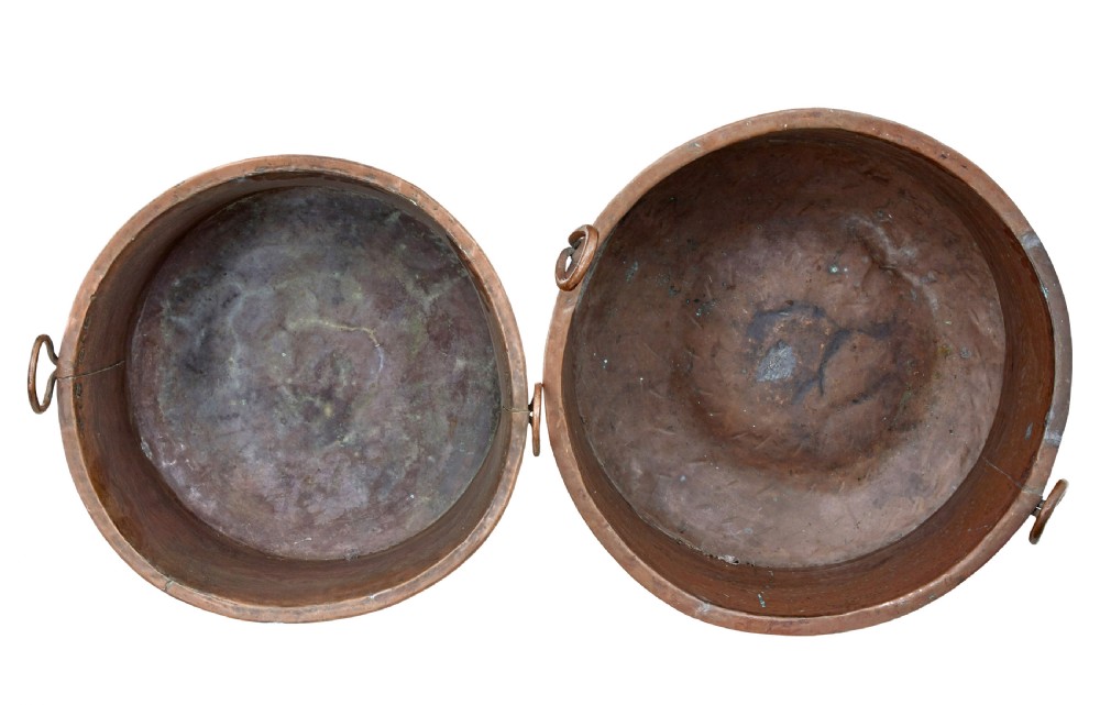 A pair of nineteenth-century hand-hammered copper cooking vessels featuring rolled rims, loop side handles, and chased decorative patterns around the bodies. View IV