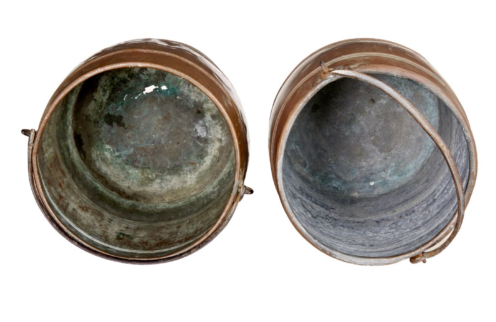 A near pair of late 19th-century cylindrical copper buckets featuring hand-hammered surfaces, reeded metal bands, and dark iron swing handles. View V