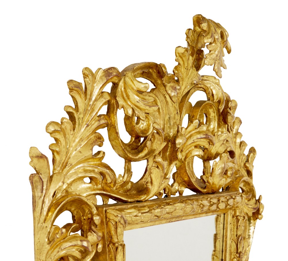 An 18th-century Italian Rococo wall mirror featuring an openwork carved giltwood frame decorated with acanthus leaf scrolls and a decorative cresting around a glass plate. View IV