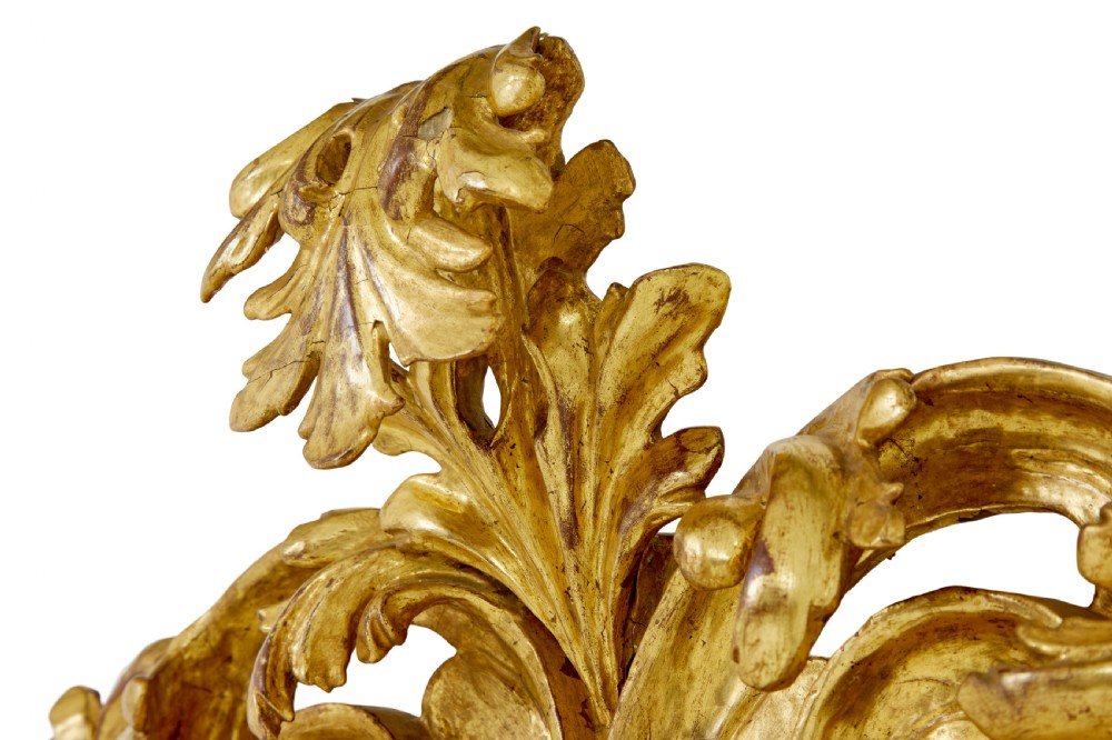 An 18th-century Italian Rococo wall mirror featuring an openwork carved giltwood frame decorated with acanthus leaf scrolls and a decorative cresting around a glass plate. View V